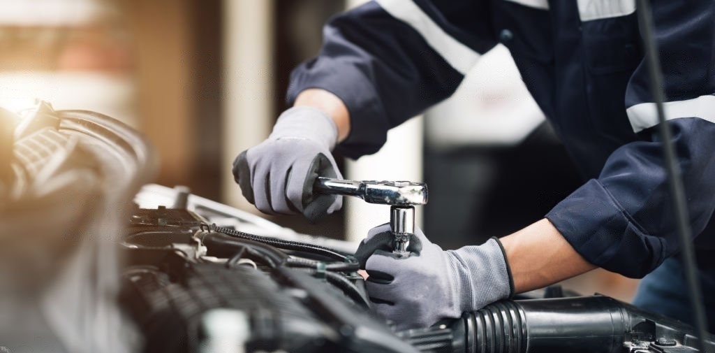 mechanic repairing kia car engine with white gloves